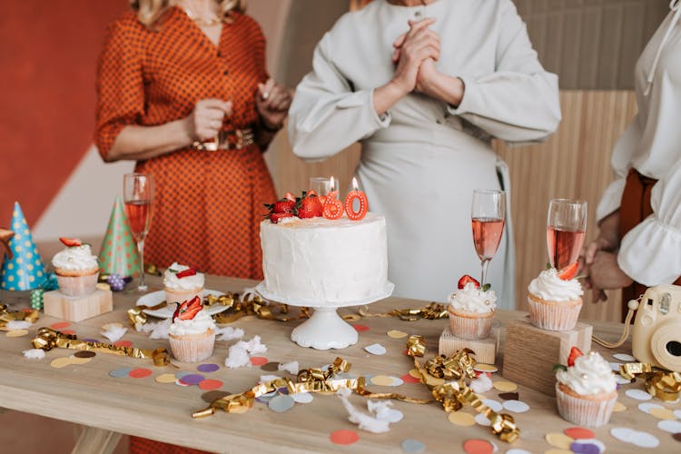 Photograph Of A Wooden Table With Cupcakes And Confetti