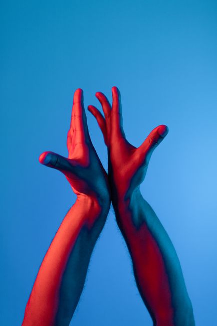 Dynamic abstract image of two hands spotlighted in red and blue tones on a blue background.