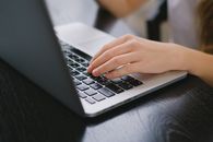 Person Using Macbook Pro on Black Table