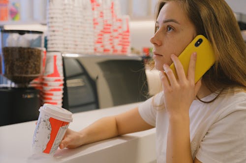 Free Woman in White Shirt Holding Yellow Cellphone Stock Photo