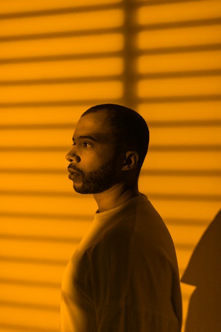 Side view portrait of a man in dramatic yellow lighting with striped shadows.