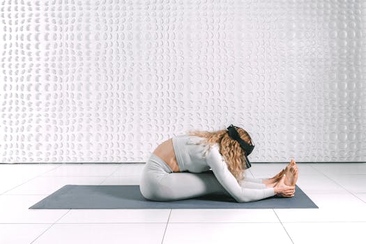 A woman engaging in a yoga stretch while wearing a VR headset in a modern indoor setting.