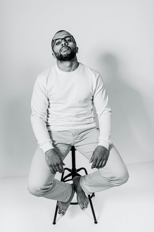 Man in White Long Sleeve Shirt and Black Framed Eyeglasses Sitting on Black Chair