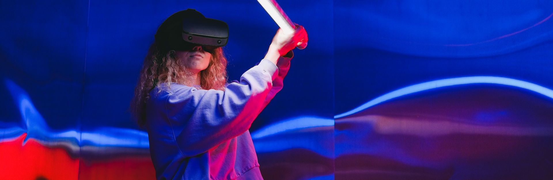 Young woman immersed in a vibrant virtual reality gaming experience indoors.