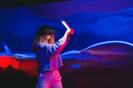 Young woman immersed in a vibrant virtual reality gaming experience indoors.