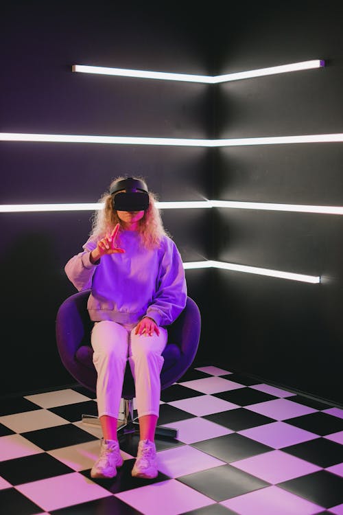 Woman Sitting in Chair and Using VR Headset
