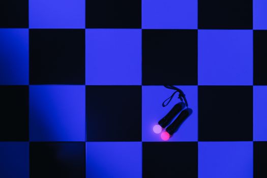 Virtual reality controllers placed on a black and blue checkered floor, emphasizing gaming technology.
