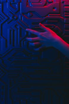 Close-up of a human hand touching a circuit board with blue and red neon lighting.