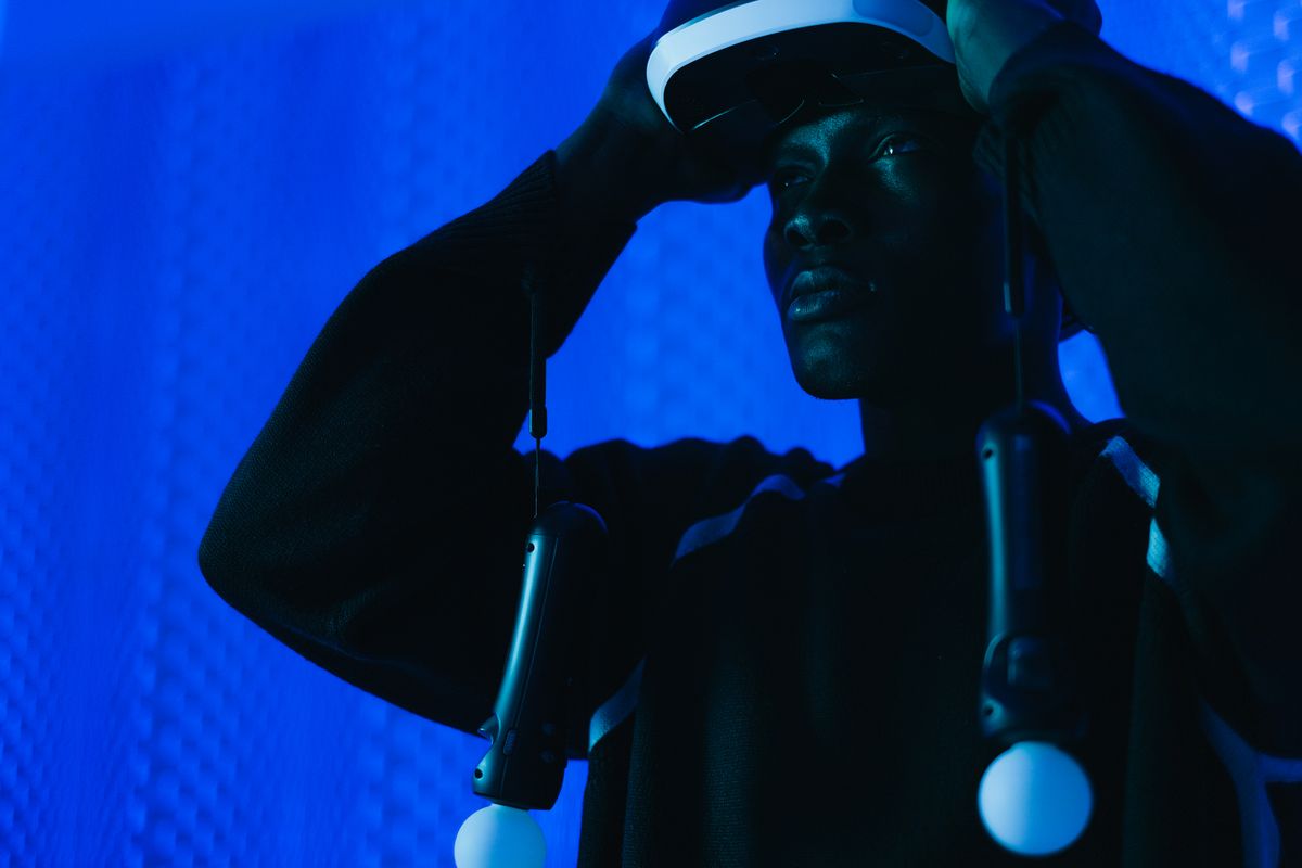 Man wearing a virtual reality headset and holding controllers in a tech-lit room