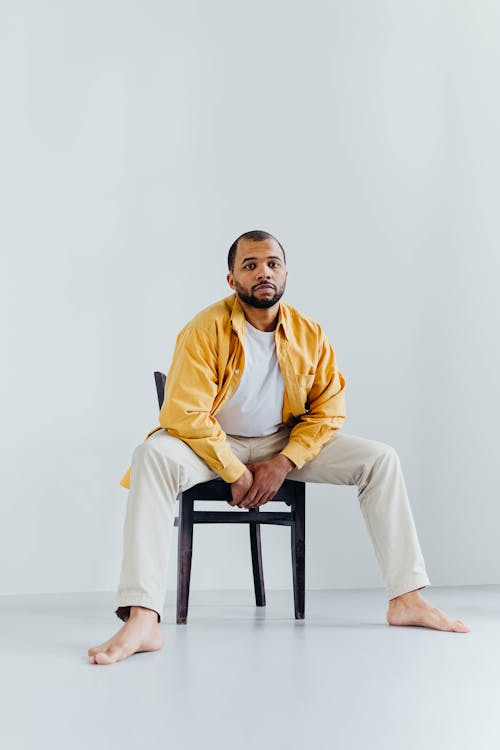 Man in Yellow Long Sleeve Shirt Sitting on Black Chair