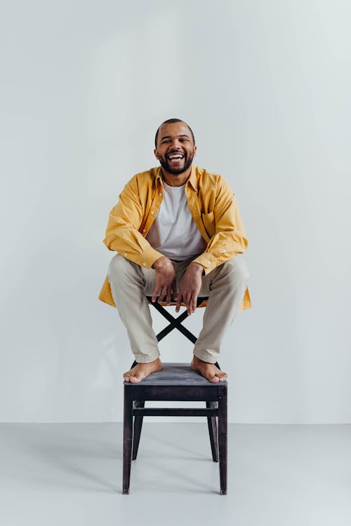 Man Laughing While Sitting on a Chair