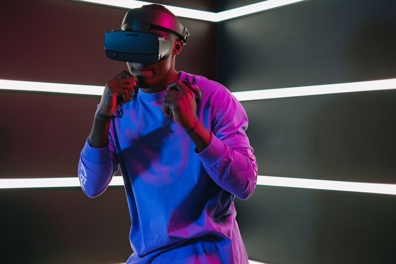 Adult player wearing a virtual reality headset in a neon-lit gaming room.