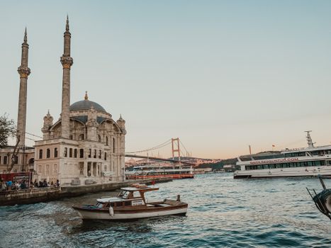 Ortaköy Mosque and boats on the Bosphorus at sunset, featuring a picturesque Istanbul skyline.