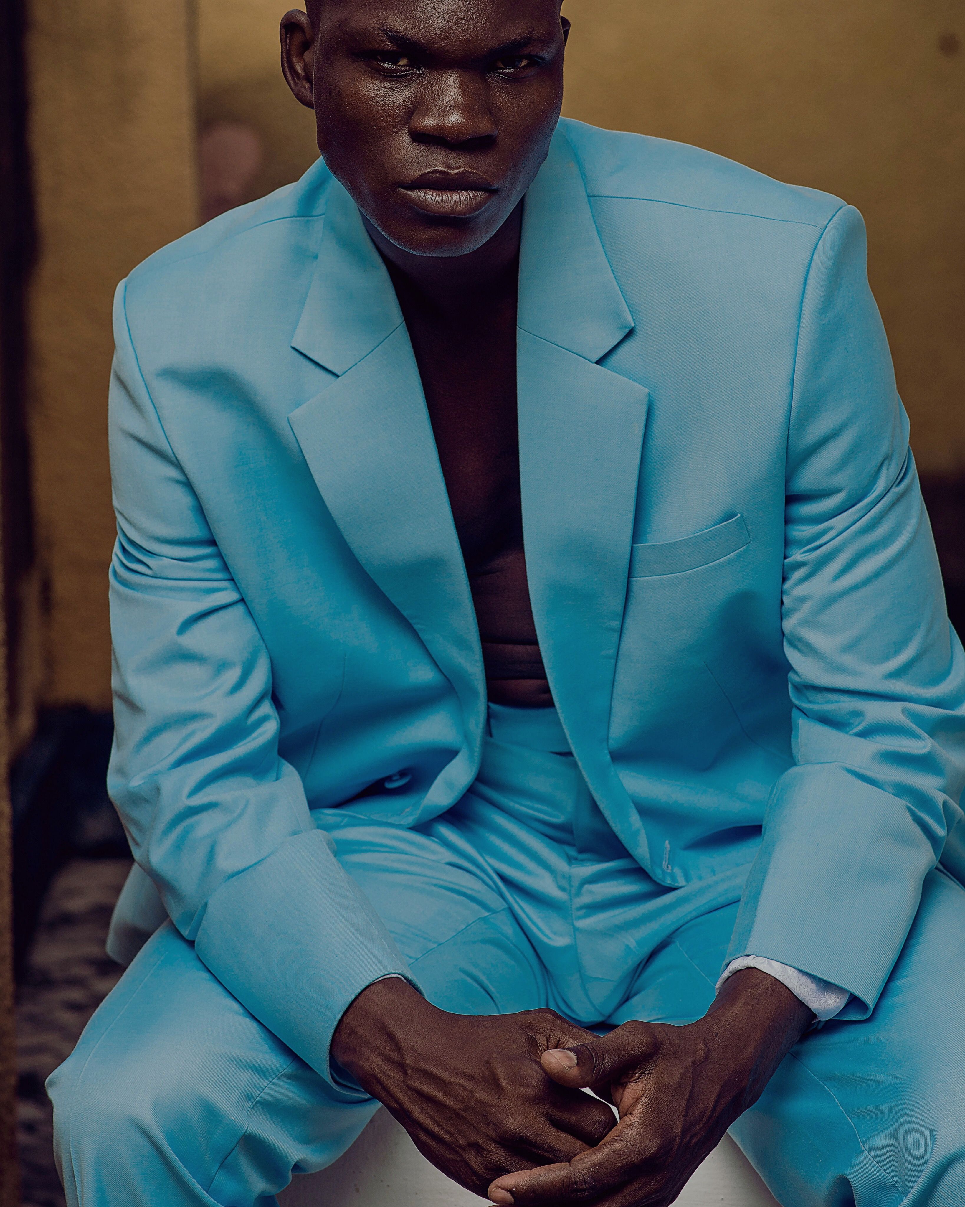 Portrait of a man in a striking blue suit, sitting with a moody expression.