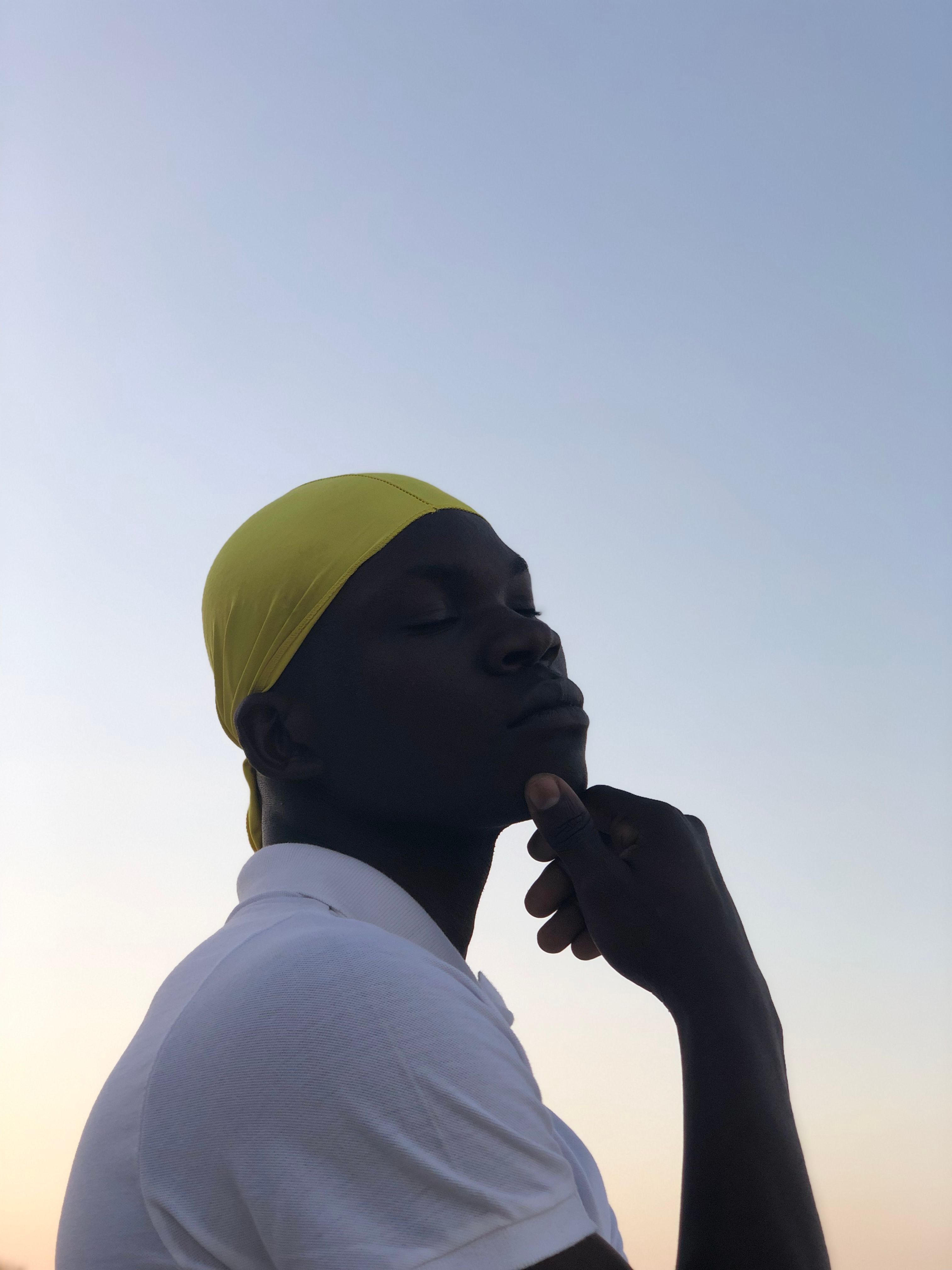 Silhouette of a man with closed eyes posing against Zanzibar's serene sky.