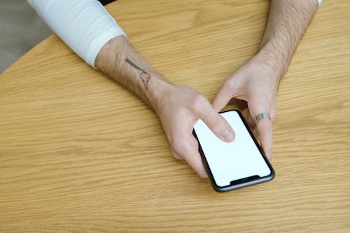 Person Holding Mobile Phone on Brown Wooden Table