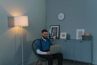 Man in Blue and White Striped Dress Shirt Sitting on Chair Using Macbook