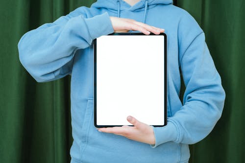 Free Person in Blue Hoodie Holding Black and White Digital Tablet Stock Photo