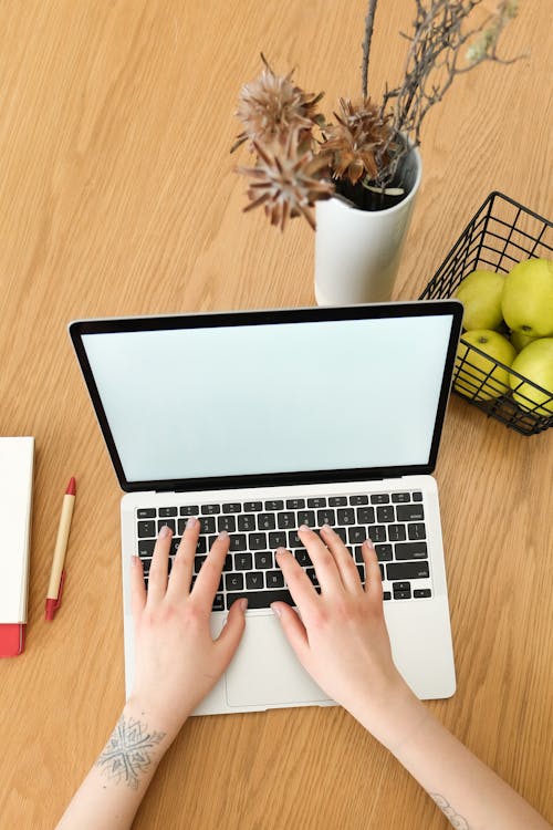 A Person using Laptop on Brown Wooden Surface