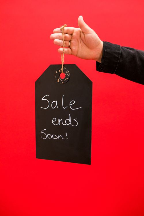 Free A hand holding a sale sign with text 'Sale ends soon!' against a vivid red background. Stock Photo