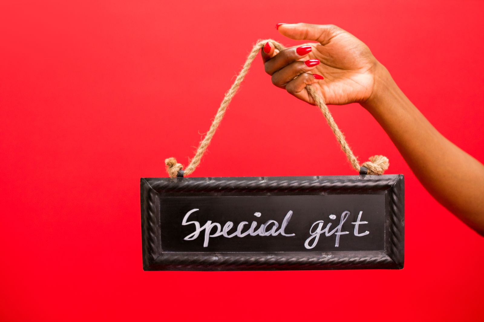 Dłoń z czerwonym manicure trzymająca tabliczkę Special gift