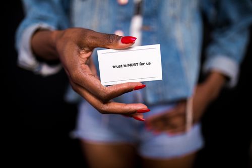 Free A close-up image of a hand holding a card with the message 'trust is MUST for us.' Stock Photo