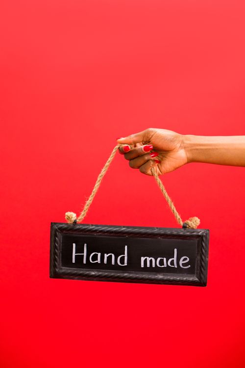 Free A hand holding a handmade sign with rope against a vibrant red backdrop. Stock Photo