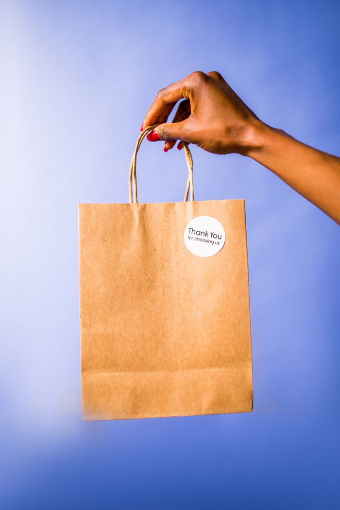 Hand holding a custom kraft paper bag with a thank you sticker