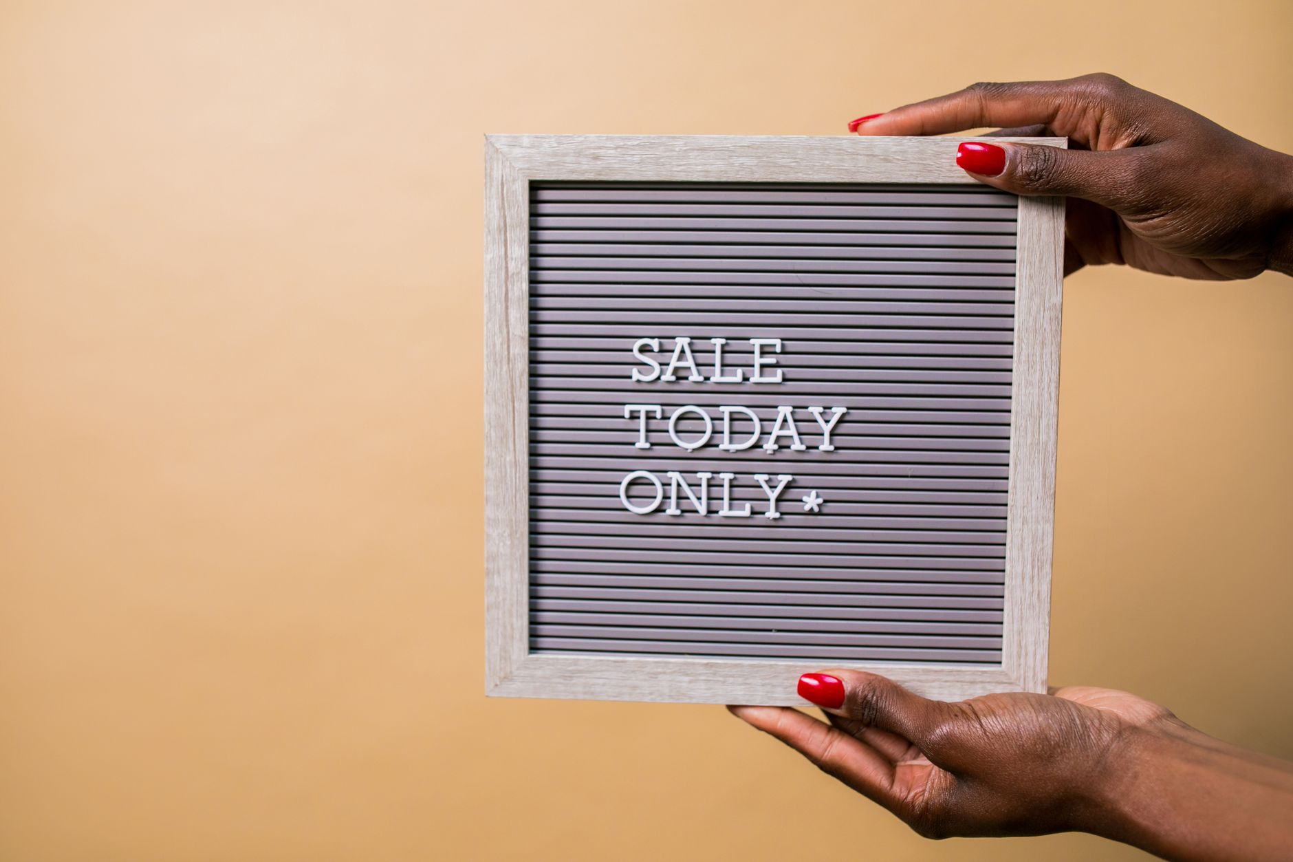 Hands with red nails holding a sign reading 'SALE TODAY ONLY' on a beige background.