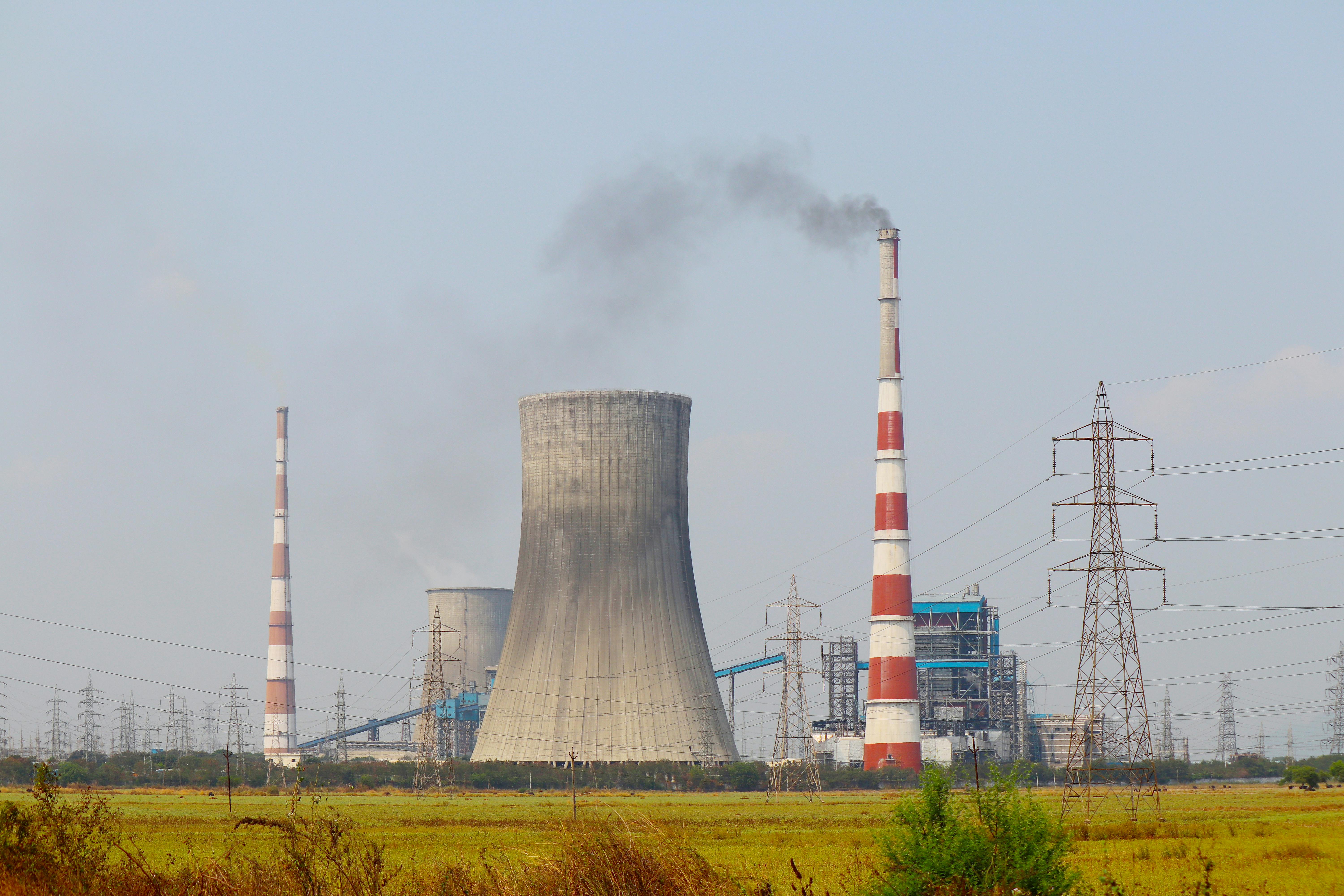 Aerial view of an industrial power plant in Vijayawada, India, with cooling towers and chimneys emitting smoke.