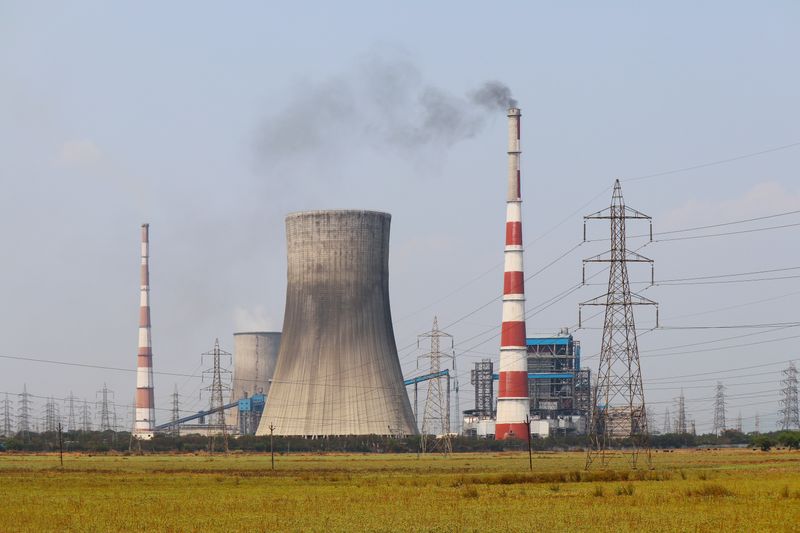 A thermal power station with a cooling tower and smokestacks beside high-voltage transmission pylons
