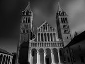 这张引人注目的黑白照片中，一座拥有高耸塔楼和拱门的大教堂映衬着暴风雨的天空