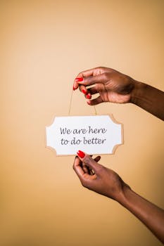 Hands holding sign with motivational message against beige background.