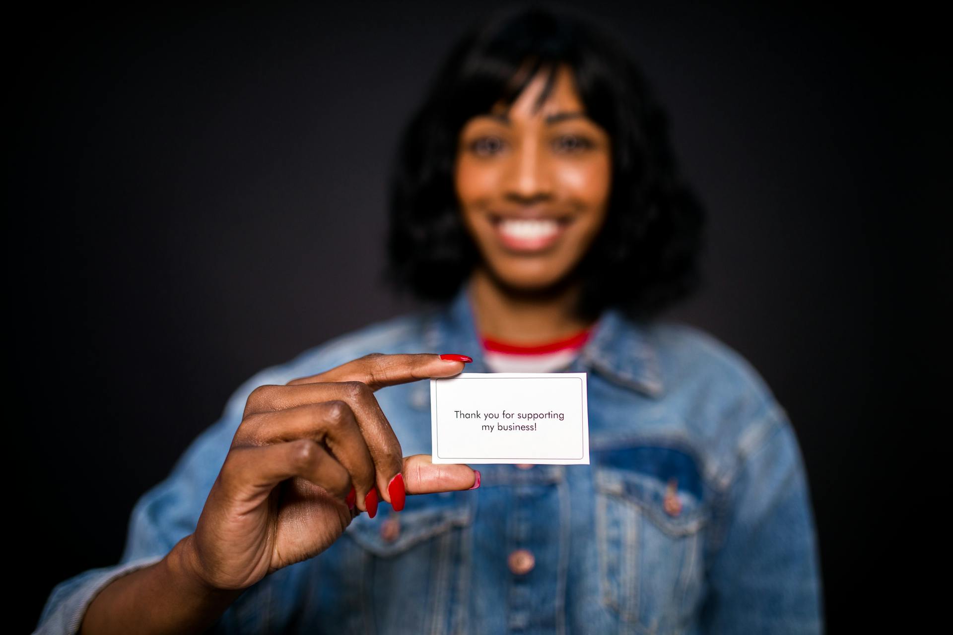 Smiling woman holding a thank you card, expressing gratitude in a business setting.