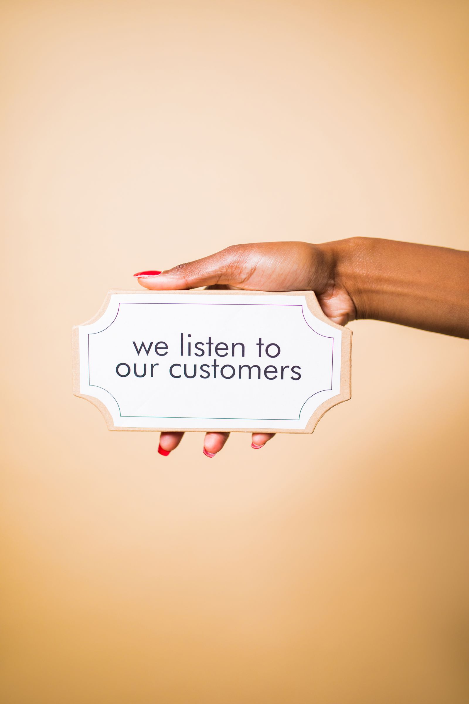 A hand holding a sign reading we listen to our customers