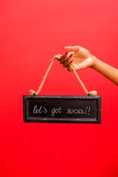 Hand holding a chalkboard sign with 'let's get social' text on a vibrant red background.