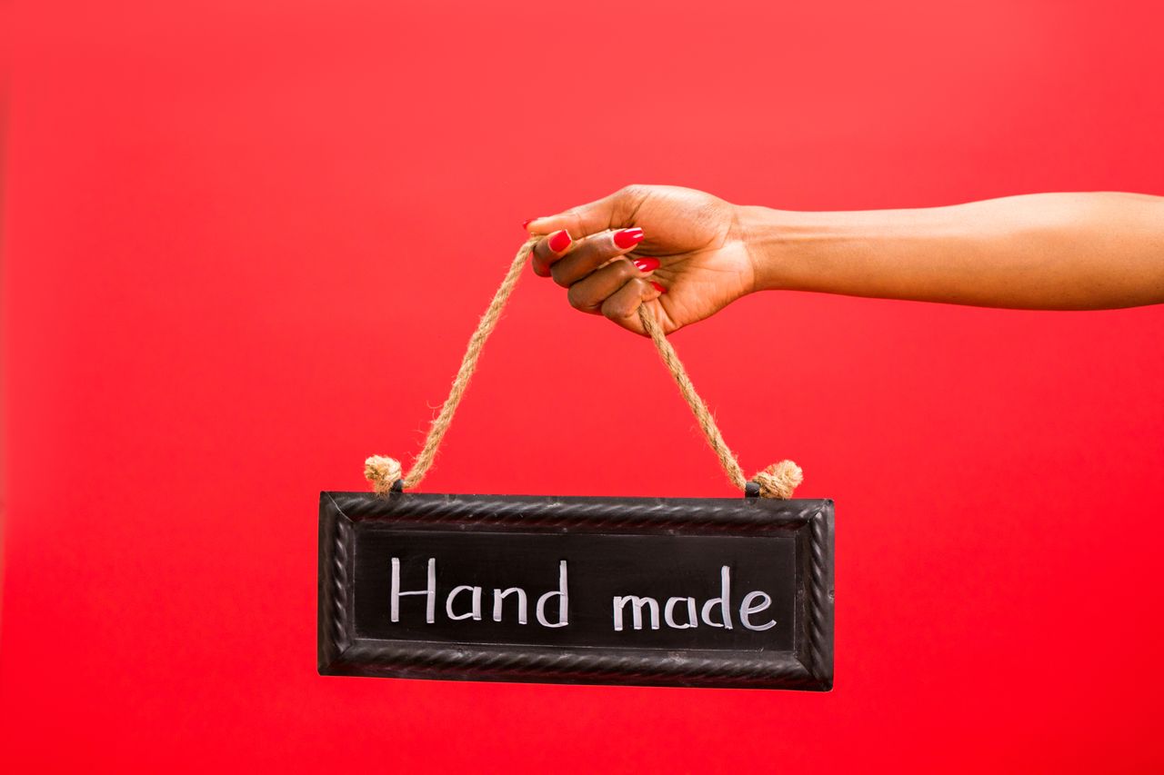 a handmade sign held by a woman against a vibrant red background symbo