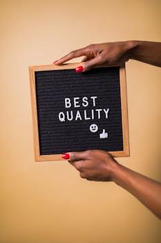 Hands holding a letter board with 'Best Quality' text, emoji, and thumbs up.