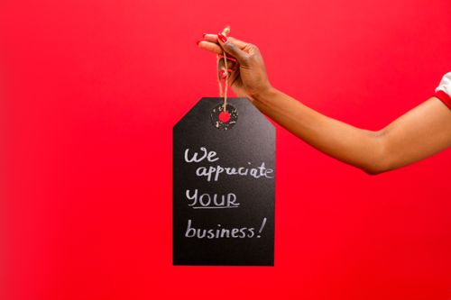 Free A hand holding a thank you sign with 'We appreciate your business!' on a red backdrop. Stock Photo