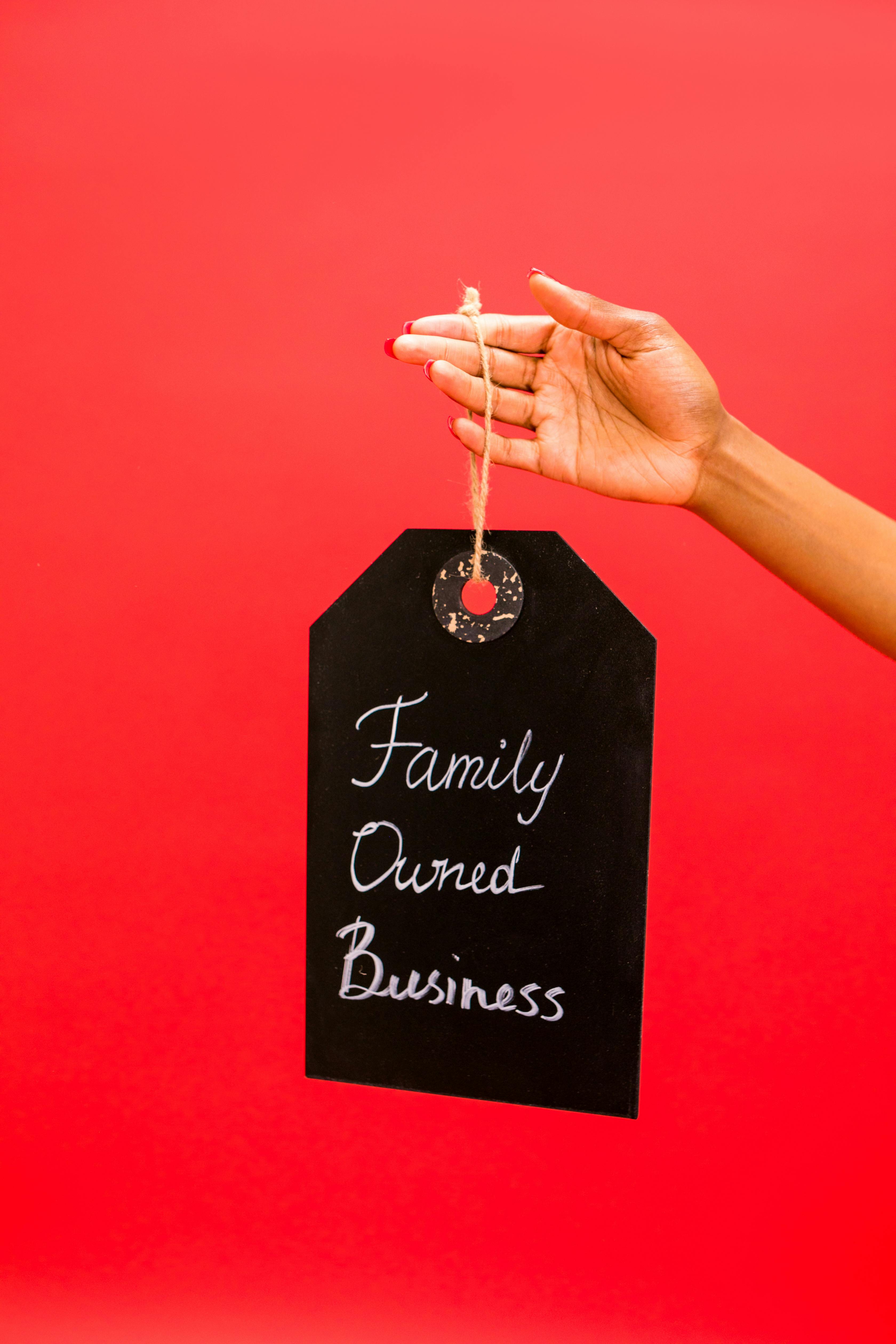 Chalkboard tag reading 'Family Owned Business' held against a vibrant red background.
