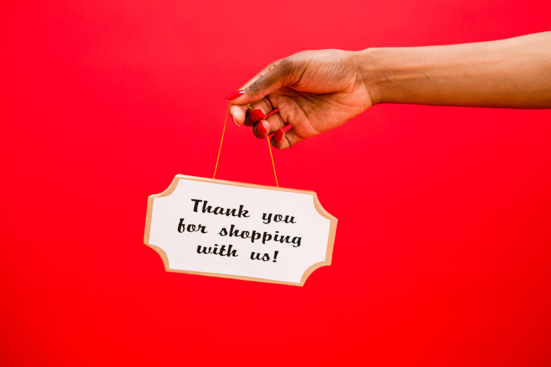 A hand holding a sign saying thank you for shopping with us