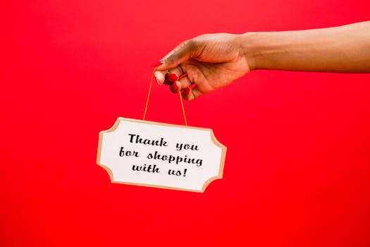 Female hand holding a sign saying 'Thank you for shopping with us!' against a vibrant red background.