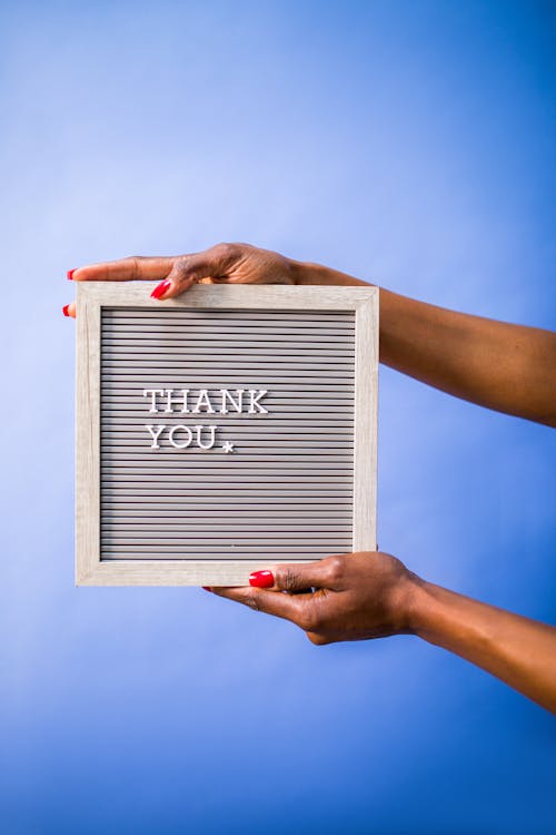 Person Holding a Board with a Text Saying "Thank You"