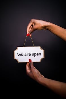 Close-up of hands holding an 'Open' sign with a black background, perfect for business promotions.