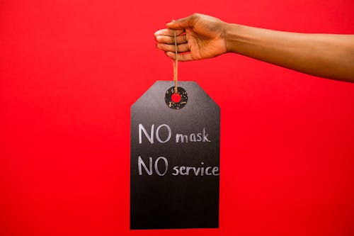 A Person Holding a Sign Board No Mask No Service
