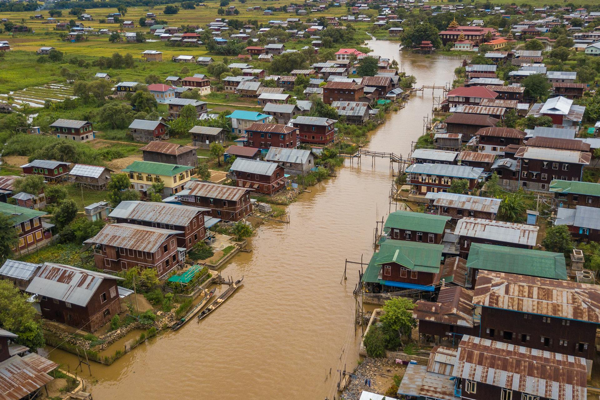 Aerial perspective of a rural village's flooded area showcasing rustic houses and water channels