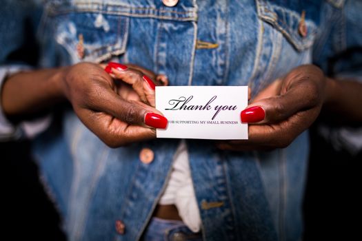 Close-up of hands holding a thank you card supporting small business.