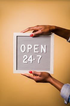 Close-up of hands holding a letter board with Open 24-7 message on a warm background.