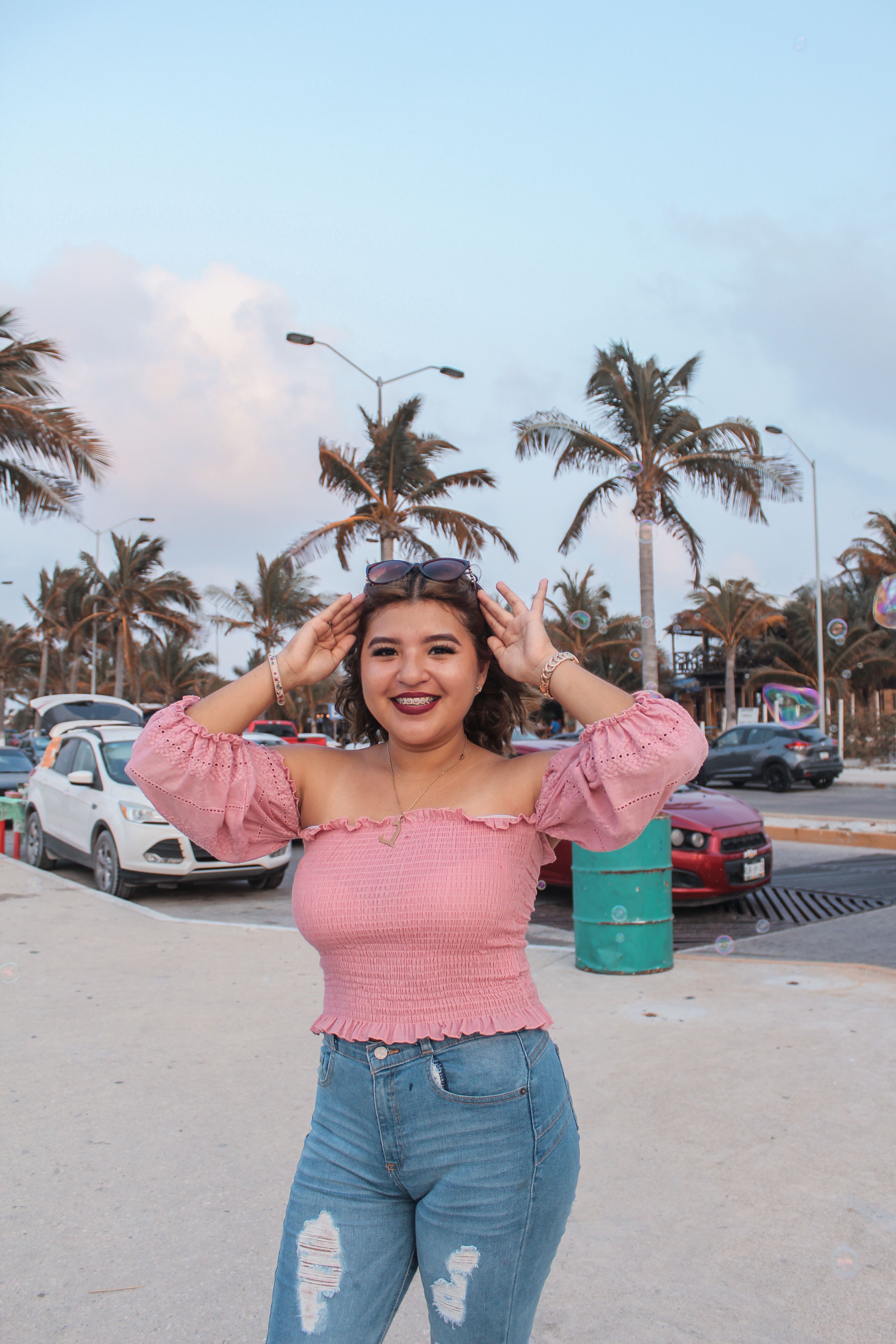 Smiling Woman Posing on Street with Palm Trees · Free Stock Photo