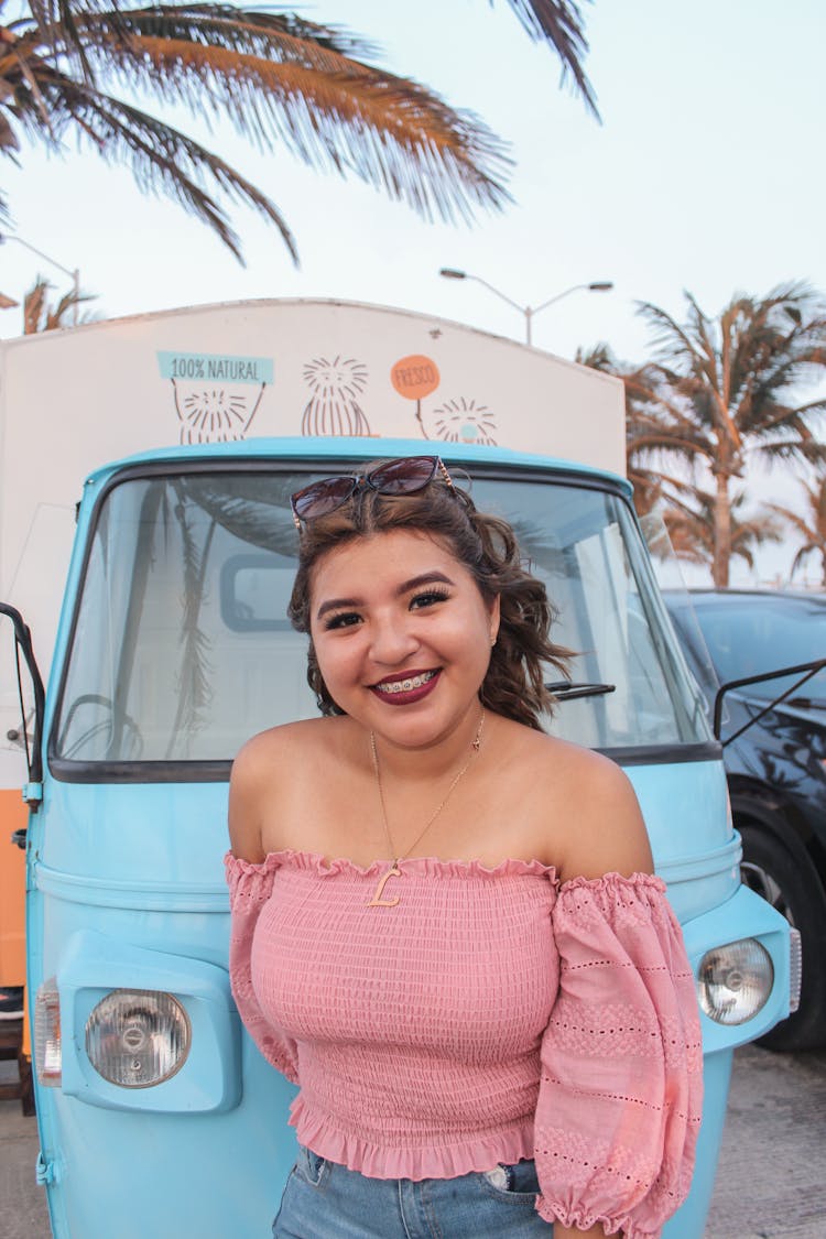 Young Woman Smiling And Standing In Front Of A Retro Ice Cream Truck 